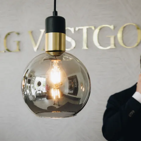 Kantoorinterieur van LG Vastgoed met stijlvolle verlichting, logo op de muur en een medewerker die telefonisch contact heeft