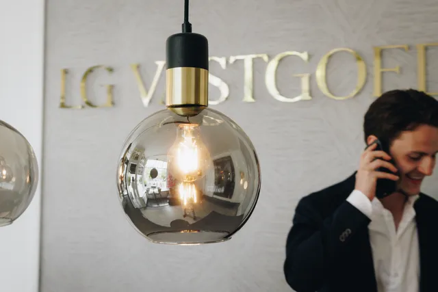 Kantoorinterieur van LG Vastgoed met stijlvolle verlichting, logo op de muur en een medewerker die telefonisch contact heeft