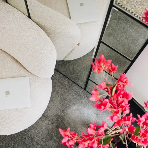 Kantoorinterieur van LG Vastgoed met een moderne loungestoel, open laptop en opvallende roze bloemen
