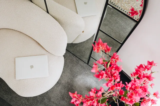 Kantoorinterieur van LG Vastgoed met een moderne loungestoel, open laptop en opvallende roze bloemen